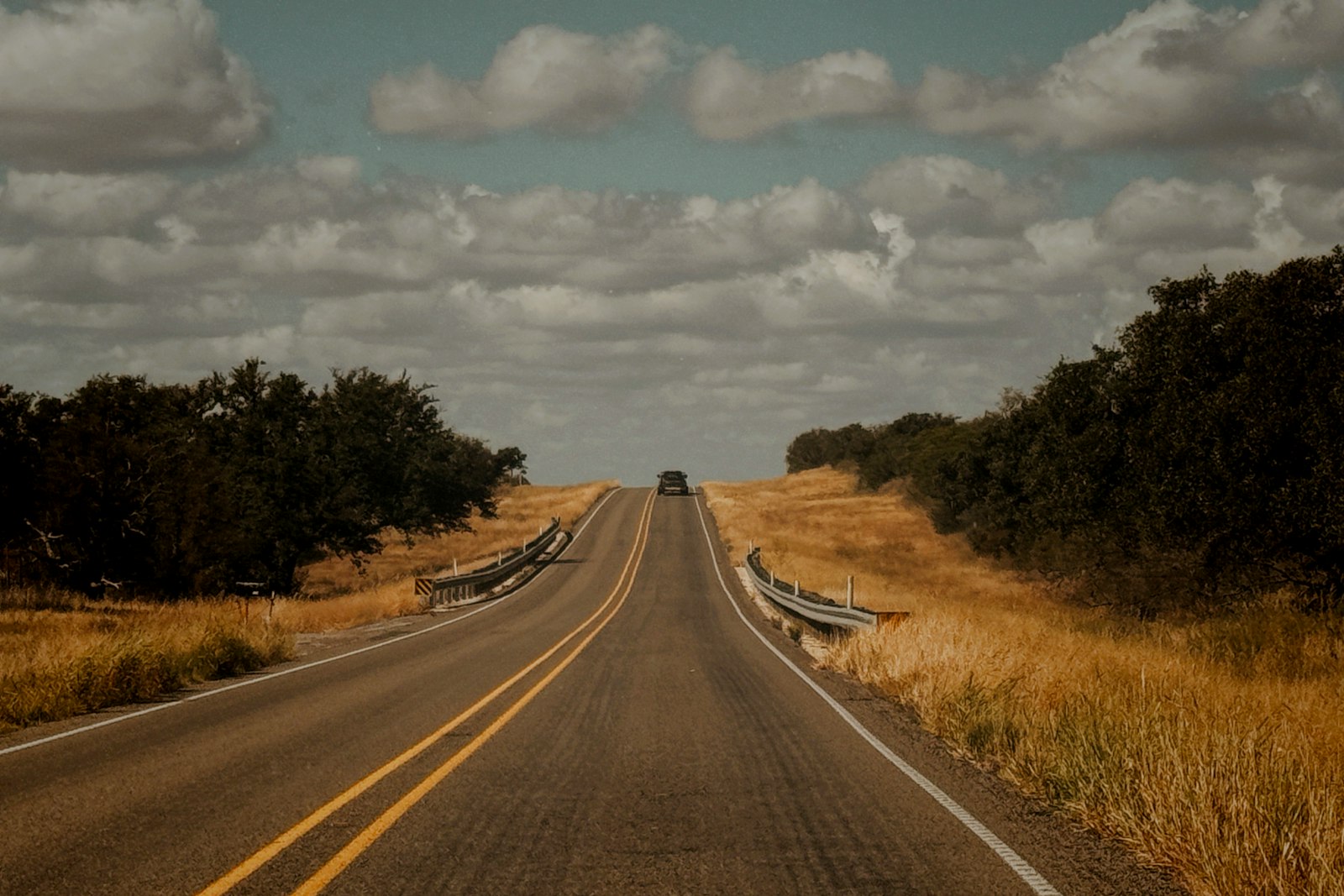 Long open Texas road with ranch fencing when moving to Texas with a car